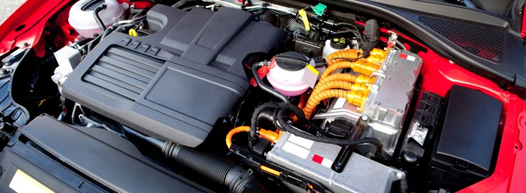 Une voiture hybride rechargeable connectée à une borne de recharge électrique.