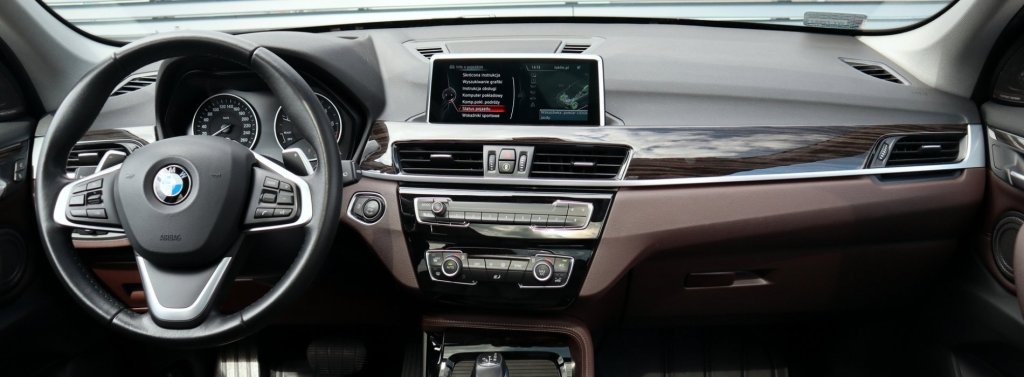 Courtage auto : Vue de l'intérieur d'une BMW X1, montrant le tableau de bord et le volant.